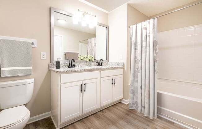 A bathroom with a toilet, sink, mirror, and shower curtain.