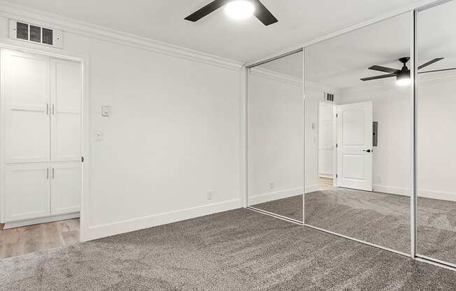 Carpeted bedroom with ceiling fan and very large closets.