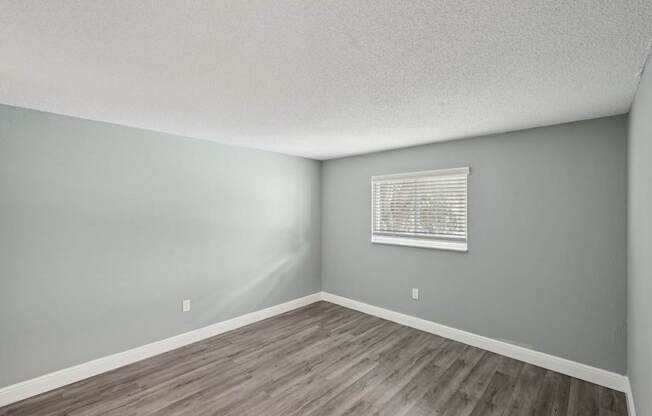 A room with a window and wooden flooring.