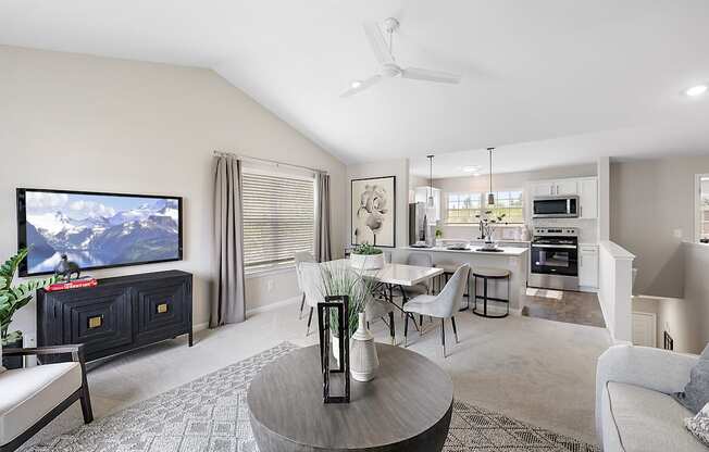 A living room with a television, a dining table, and chairs.