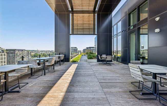 A patio with tables and chairs overlooking a cityscape.