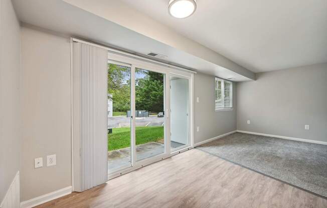 an empty living room with sliding glass doors to a yard at ReNew Odenton