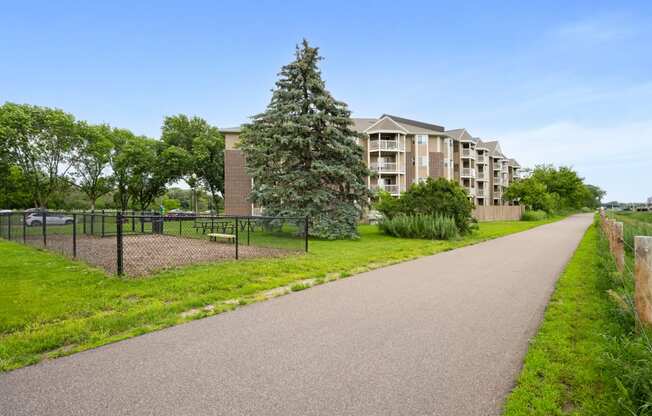 a walkway with a building in the background and a tree in the grass