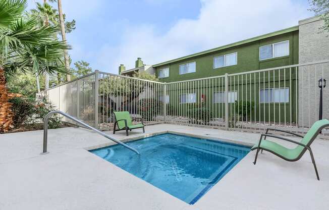A pool surrounded by a fence and chairs.