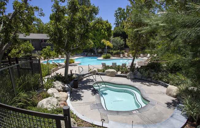 a pool and spa at an apartment community with trees