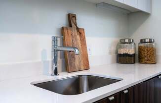 a kitchen sink with a wooden cutting board on the wall