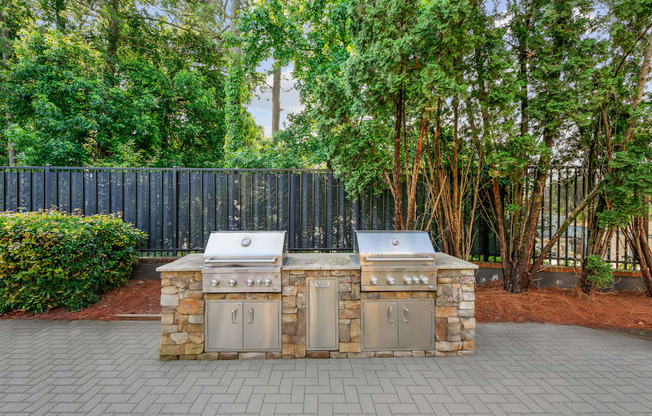 A stone and metal outdoor kitchen with a grill and sink.