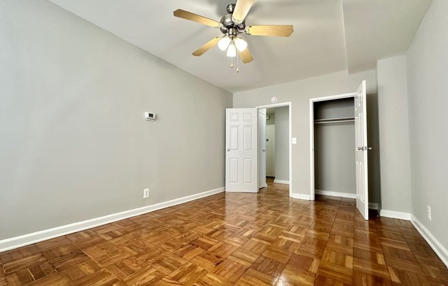 an empty living room with wood flooring and a ceiling fan