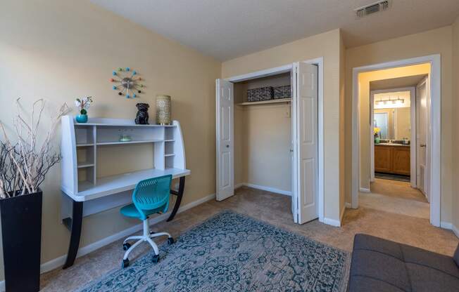 a home office with a desk and a chair and a door to a bathroom