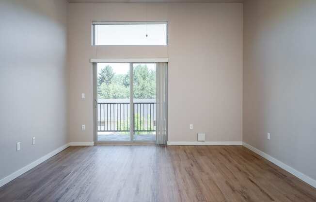 an empty living room with a sliding glass door leading to a balcony