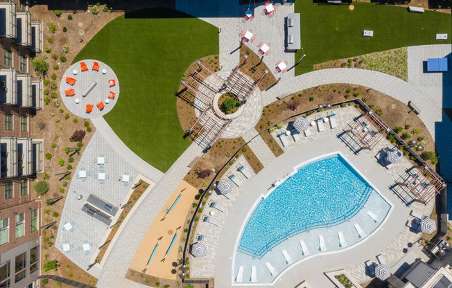 Beautiful drone shot of courtyard with pool, grills, and firepit at Link Apartments® Linden in Chapel Hill