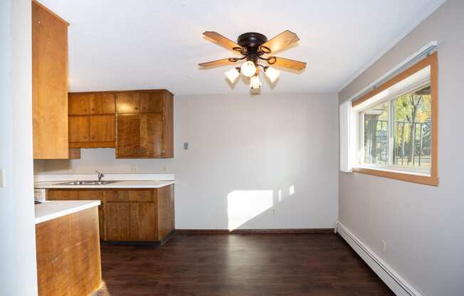 an empty kitchen with a ceiling fan and a window. Fargo, ND Country Club Apartment