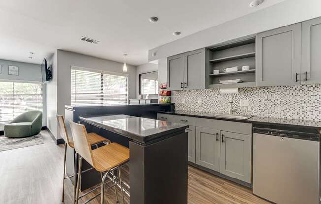 A kitchen with a black countertop and wooden chairs.