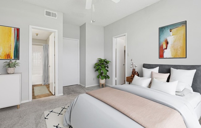 A bedroom with a large bed and a painting on the white wall at Jefferson Creek Apartments in Irving, TX
