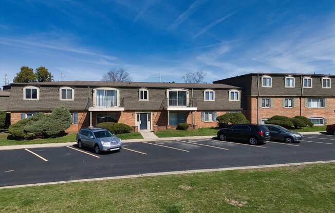 an apartment building with cars parked in the parking lot