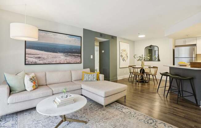 A living room with a white couch and a large landscape painting on the wall.