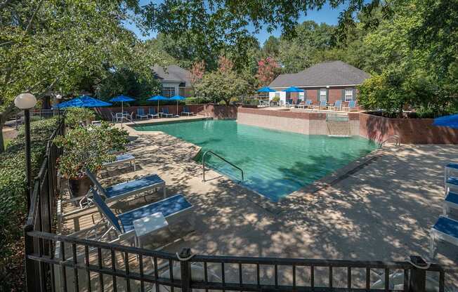 A pool surrounded by trees and a fence.