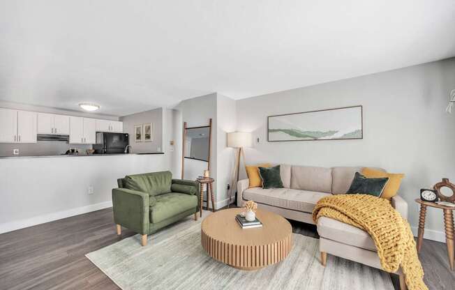 A living room with a green armchair, a beige sofa, and a wooden coffee table.