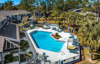 A swimming pool surrounded by a fence and chairs.
