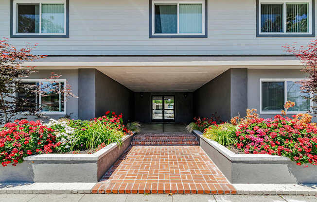 A house with a grey facade and a brick pathway leading to the entrance.