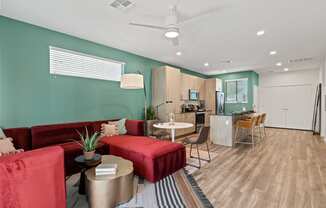 a living room with red couches and a kitchen with a table and chairs