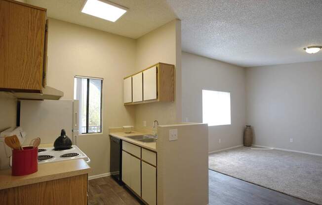 A kitchen with white cabinets and a red pot on the stove.