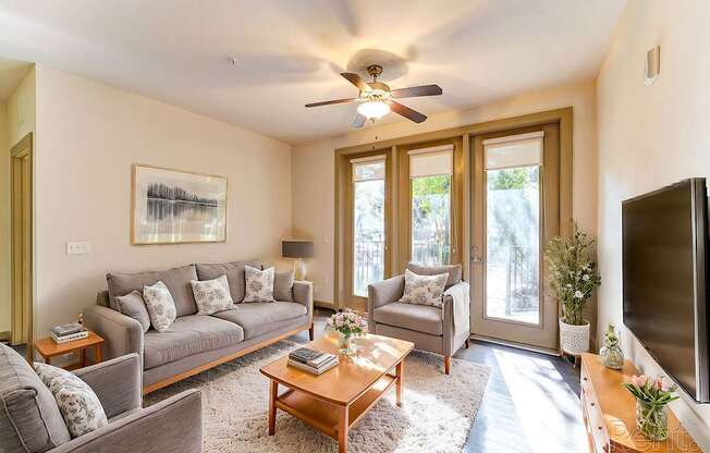 A living room with a grey couch, a coffee table, a television, and a painting on the wall.