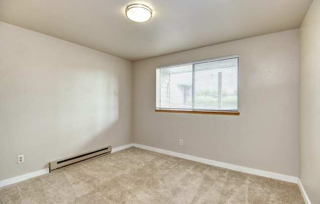 a bedroom with carpet and a window.