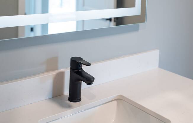 a bathroom sink with a black faucet and a mirror