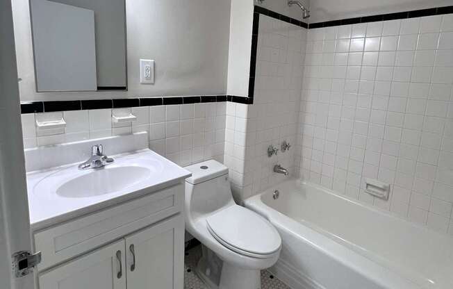 A white toilet sits in a bathroom next to a white sink.