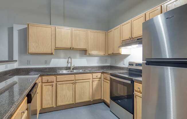 an empty kitchen with stainless steel appliances and wood cabinets