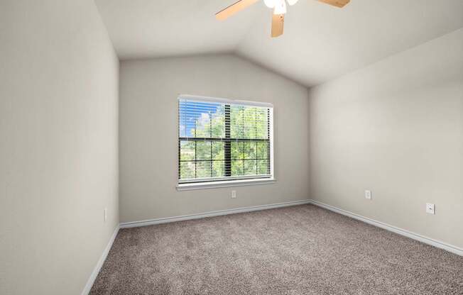 A room with a window and a ceiling fan.