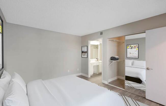 A bedroom with a white bed and a mirror on the wall.