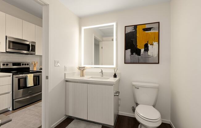 A bathroom with a toilet, sink, and a painting on the wall.