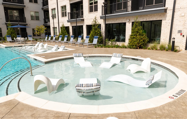 The pool lounge at our apartments for rent in Atlanta, featuring chairs in the pool and a view of the apartment complex.