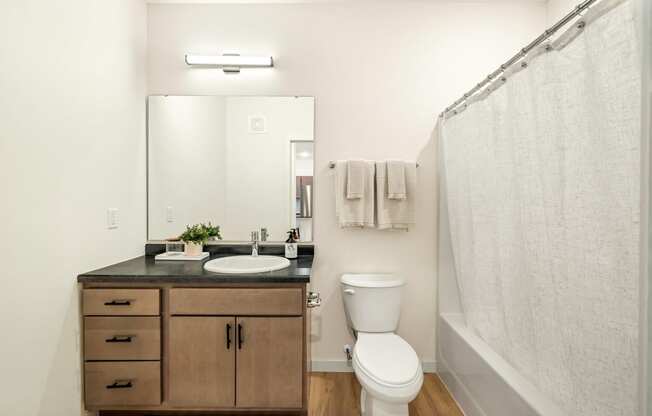 a bathroom with a toilet sink and mirror and a shower at The Standard on 32nd, West Fargo, ND