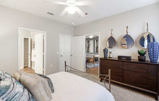a bedroom with a bed and a dresser and a ceiling fan at Cumberland Place Apartment Homes, Texas 75703