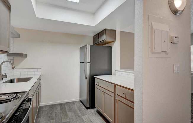 A kitchen with a stainless steel refrigerator and wooden cabinets.