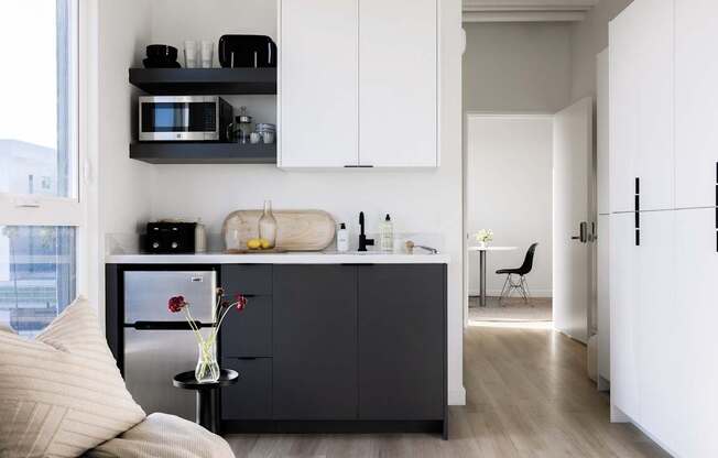 A modern kitchen with white cabinets and a black fridge.