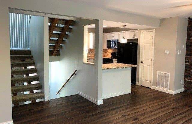 a living room with a staircase and a kitchen
