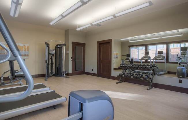 A gym with treadmills, weights, and exercise equipment. at Mill Creek Meadows Apartments, Mill Creek, Washington