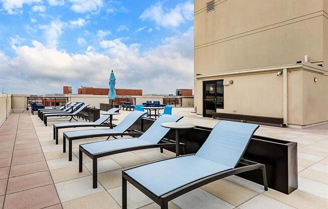 a row of lounge chairs and tables on a rooftop patio