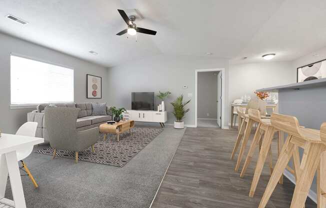 Wide view of living room filled with natural light from the large window above the gray couch.