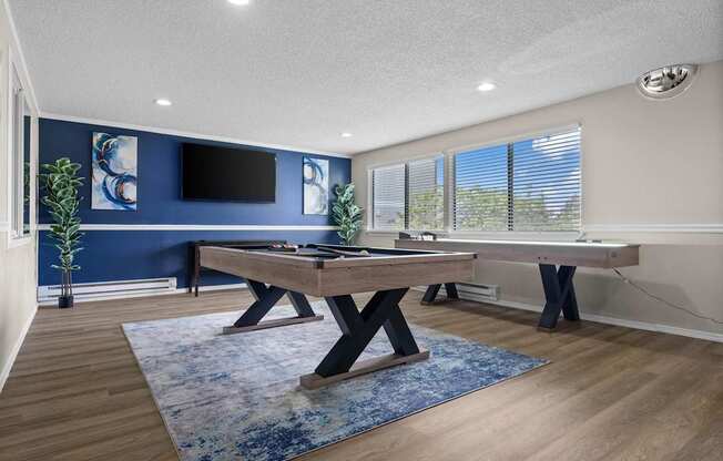 A room with a pool table and a tv on the wall.