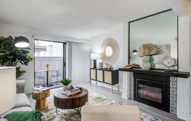 Fusion Warner Center apartments living room with elegant natural decor, electric tile fireplace and sliding glass door to patio.