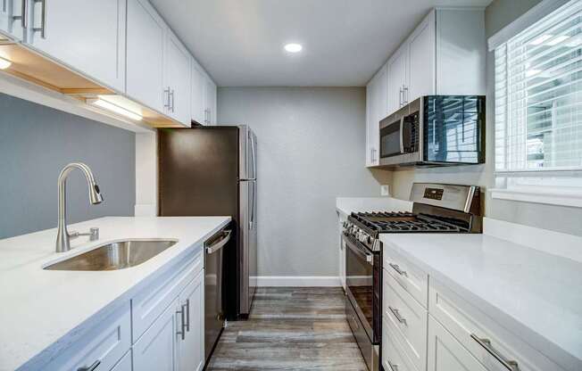 A kitchen with white cabinets and a black refrigerator.