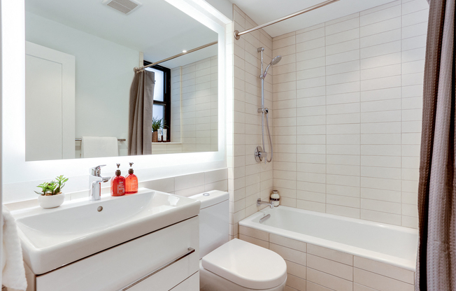 Bright tiled bathrooms with large backlit designer mirror, Hans Grohe chrome fixtures and Villeroy & Boch vanity