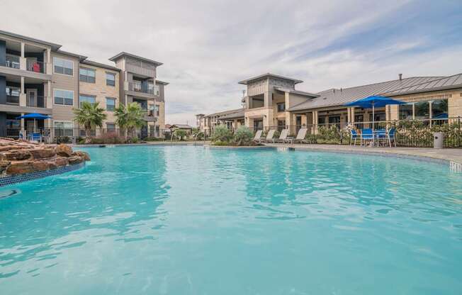 A swimming pool in front of a building with a blue sky in the background.