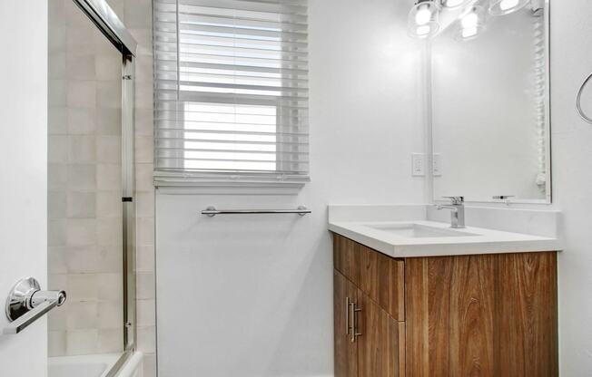 a bathroom with a sink and shower and a mirror