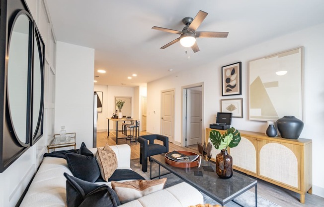 a living room with white walls and a ceiling fan